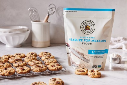 Bag of gluten-free measure for measure flour next to cooling rack full of chocolate chip cookies