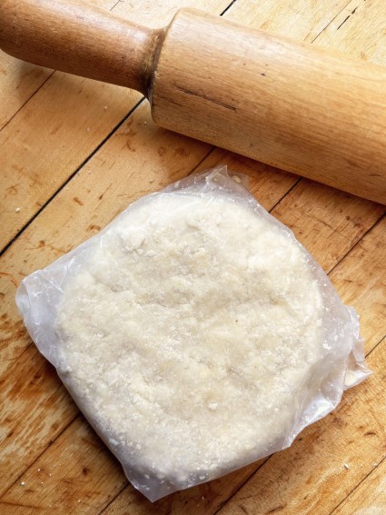 Pie pastry shaped into a disk and wrapped in waxed paper prior to refrigeration.