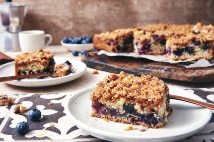 Two pieces of breakfast cake cut into pieces resting on plates. 