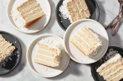 Rectangular slices of four-layer coconut cake with coconut frosting on serving plates. 