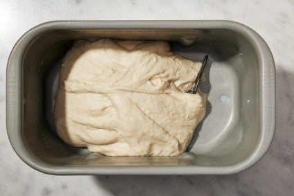 Bread machine bucket with bread dough in it, all on the left side