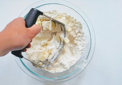 Using a pastry blender to mix fat into flour for pie crust.