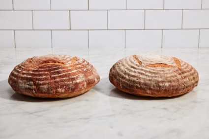 Two boules of baked bread next to each other, one with more even browning