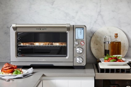A Breville Smart Oven Air Fryer Pro on a countertop next to several kitchen items