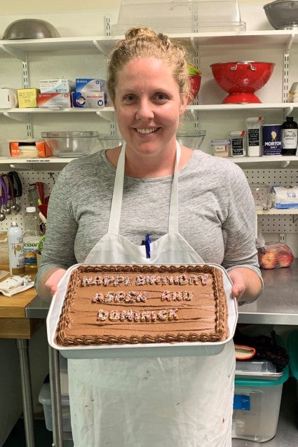 Molly holding up a birthday cake she baked to donate