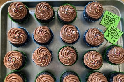 Sheet pan of chocolate cupcakes with marker with birthday wishes