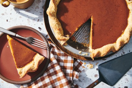 A pumpkin pie with a slice removed on a plate
