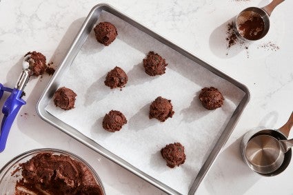 Chocolate cookie dough spaced several inches apart on a parchment-lined baking sheet