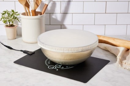 Bowl of covered bread dough proofing on dough riser