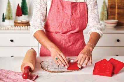Baker cutting out gingerbread house dough with pop-out cutters