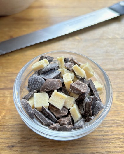 Chopped white, milk, and dark chocolate chunks in a small bowl.