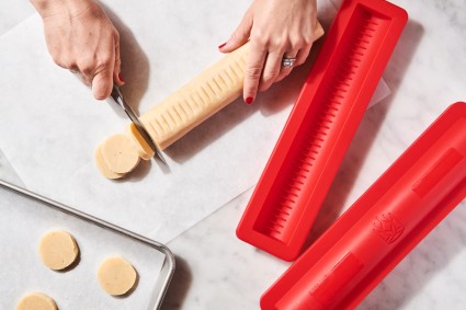 Baker slicing log of cookie dough next to slice-and-bake cookie keeper