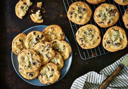 A plate of classic chocolate chip cookies next to a few cookies with bites taken out of them