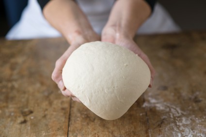 Baker's hands holding smooth kneaded bread dough
