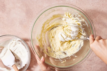 Baker folding whipped cream into pastry cream to make diplomat cream