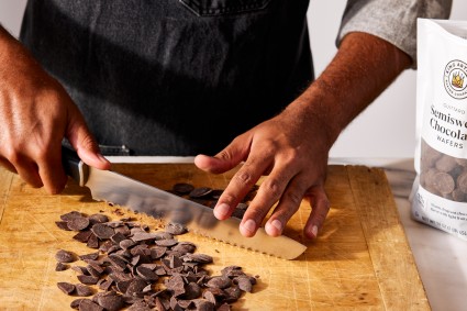 Baker chopping chocolate with serrated knife 