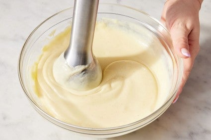 A baker using an immersion blender to make silky pastry cream