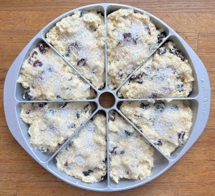 Scone dough in a standard eight-well metal scone pan, topped with sparkling sugar and ready to bake.