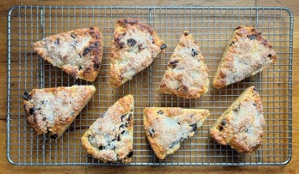 Eight triangular baked scones arrayed on a metal cooling rack.