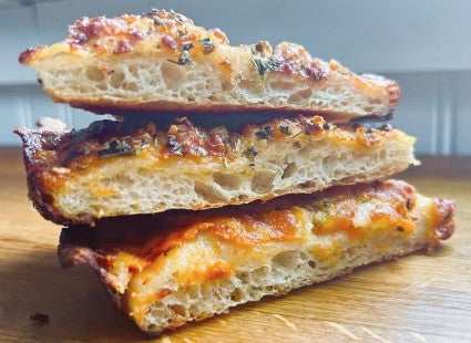 Three slices of baked pizza, stacked atop one another, showing the light, hole-y interior of the crust.