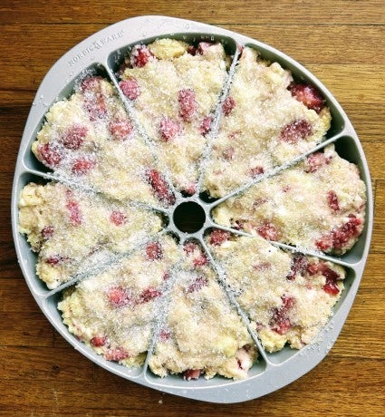 Fresh strawberry scone dough pressed into the wells of a standard scone pan, ready to be baked.