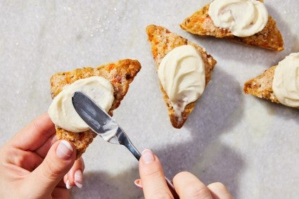 Baker frosting a carrot cake scone