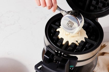 Baker pouring batter into Belgian waffle iron