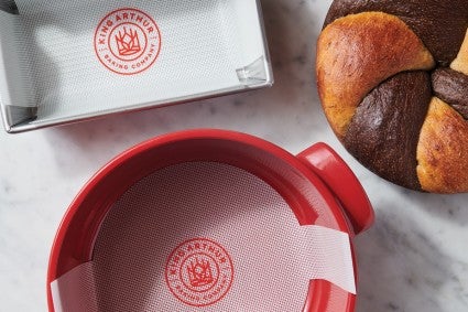 Loaf pan and Dutch oven lined with reusable liners, next to a baked Marble Rye