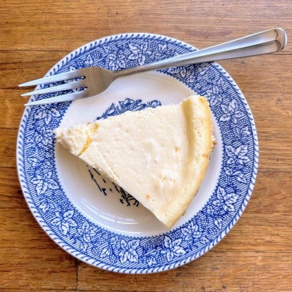 Slice of cheesecake on a plate showing raised, slightly browned edge, a sign of overbaking.