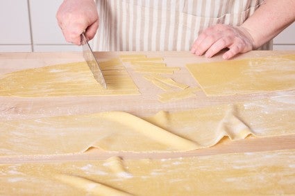 Slicing homemade egg noodle dough 