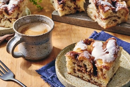 Cinnamon rolling focus on a plate with a cup of coffee