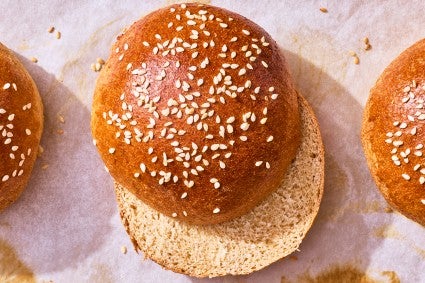 100% Whole Wheat Hamburger Buns sliced and on parchment paper
