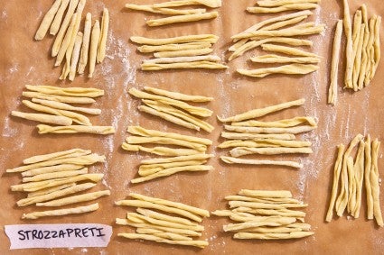 Strozzapret's macaronas shape on a parchment line baking sheet
