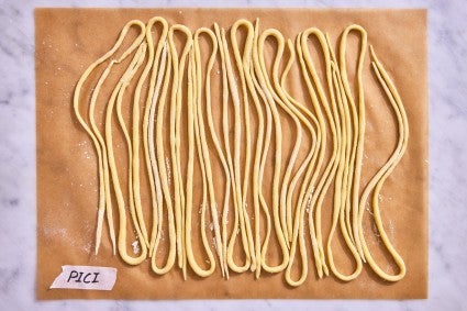 Pici pasta shape on a parchment line baking sheet