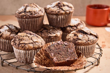 Chocolate Zucchini Muffins on a cooling rack with one halved
