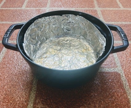 Dutch oven lined with aluminum foil, both bottom and sides. 
