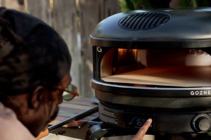 Becker adjusting the temperature on a gansney pizza oven