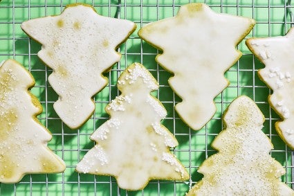 Two rows of Christmas tree shaped cookies on a drying rack creatively arranged so that one row creates a pattern with the other.