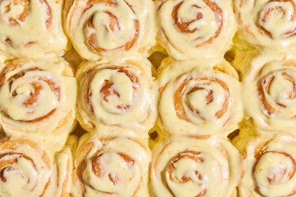 Detail shot of several Fluffy Frosted Orange Rolls together seen from above with a glossy yellow citrus glaze.