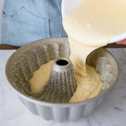 Yellow cake batter being poured into a Bundt pan.
