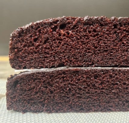 Two layers of chocolate cake stacked one atop the other to show their identical height and texture.