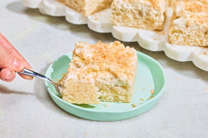 A slice of Creamy Coconut Sheet Cake on a plate with a bite on a fork