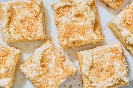 Creamy Coconut Sheet Cake shown sliced and arranged on a counter.