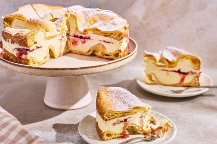 Karpatka Cake on a cake stand with slices on plates.