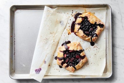 Parchment used to bake galettes halfway pulled back to show clean sheet pan beneath 