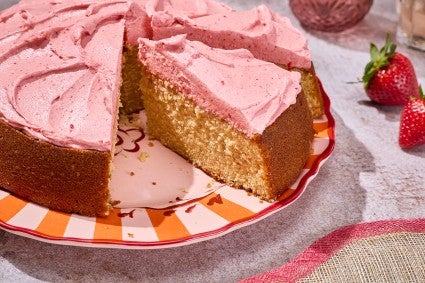 Brown Sugar Strawberry Frosted Cake seen from the side showing a thick layer of frosting and a golden cakey interior.