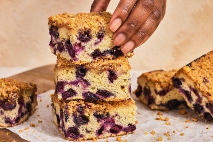 A stack of Emancipation Breakfast Cake slices with a hand placing the top slice