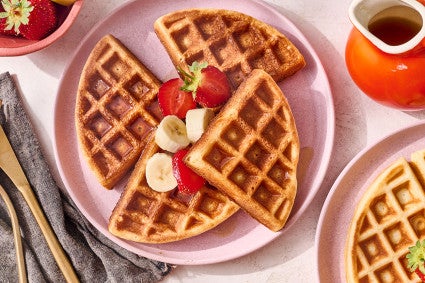 A Belgian Style Yeast Waffle on a plate with fresh strawberries and banana.