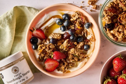 Sourdough Granola atop some yogurt in a bowl along with fresh fruit