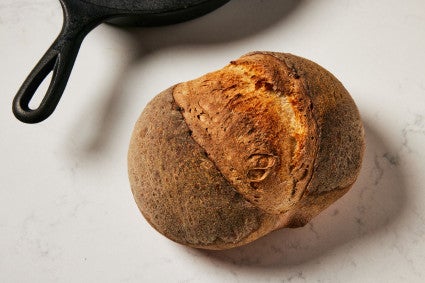 Bread with a dull crust next to cast iron pan 